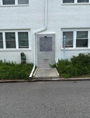Un edificio con fachada blanca, una puerta con un pequeño ventanal y una estatua de una figura.