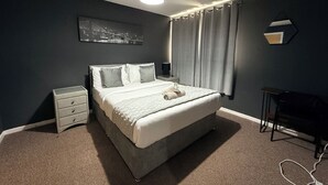 Une chambre à coucher avec un lit, une table de chevet et un bureau.