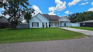 A two-story house with a covered porch, a well-maintained lawn, and a clear sky.