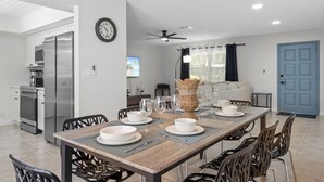 Un espace repas moderne avec une table en bois, des chaises et une cuisine en arrière-plan.
