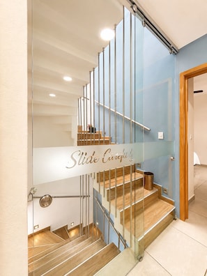 A modern staircase with glass railings and wooden steps.