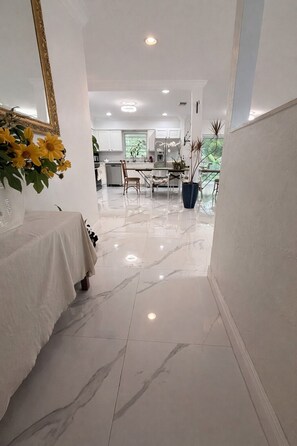 Un pasillo con piso de mármol que conduce a una zona de cocina.