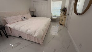Une chambre à coucher avec un lit, une commode, un miroir et une fenêtre avec des stores.