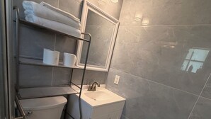 Une salle de bain équipée de toilettes, d’un lavabo, d’un porte-serviettes et d’un miroir.
