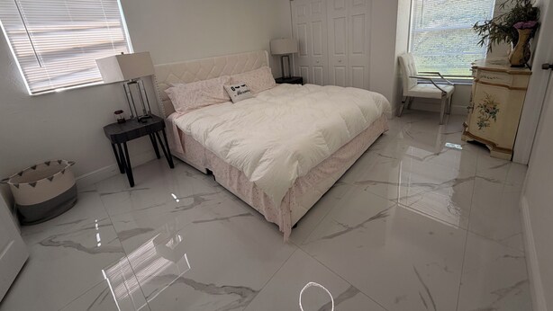 Une chambre à coucher avec un lit, des tables de chevet, une commode et une fenêtre avec des stores.