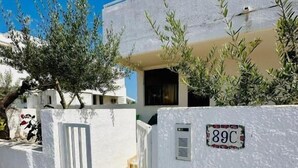 A white building with a gate, a small staircase, and a sign indicating 89C. - Giardino dei Trulli Villa al Mare (Capitolo)