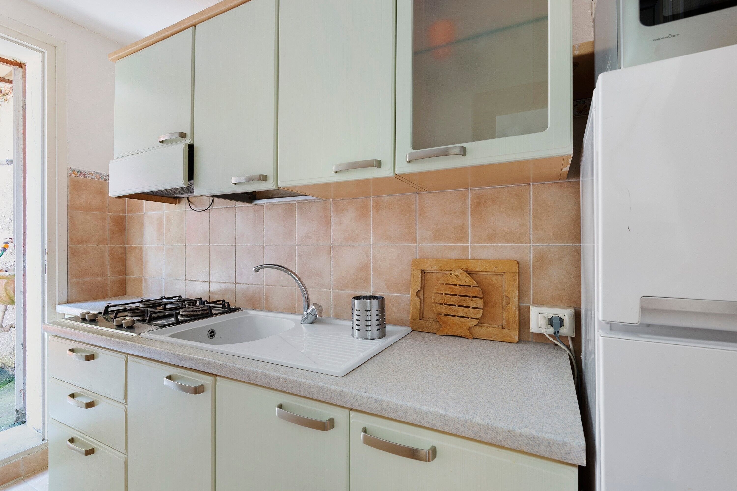 A kitchen with a gas stove, sink, and wooden cutting board.