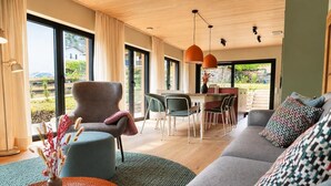 Ein modernes Wohnzimmer mit Sofa, Sessel und Essbereich.