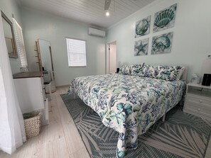 A bedroom with a bed, a dresser, a mirror, and a window with blinds.