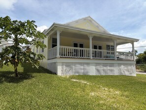 A two-story house with a covered porch and a small tree in the front yard.