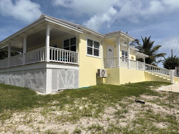 A two-story house with a covered porch, a staircase, and a small lawn.