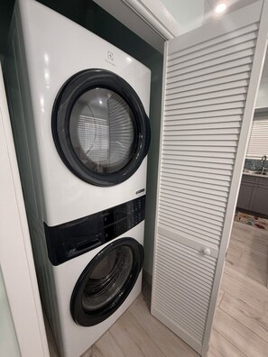 En kompakt, vit tvätt- och torkmaskin som monteras på väggen, med en kontrollpanel och en rund lucka.