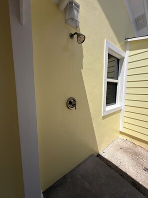A yellow exterior wall with a white window, a wall-mounted light fixture, and a doorbell.