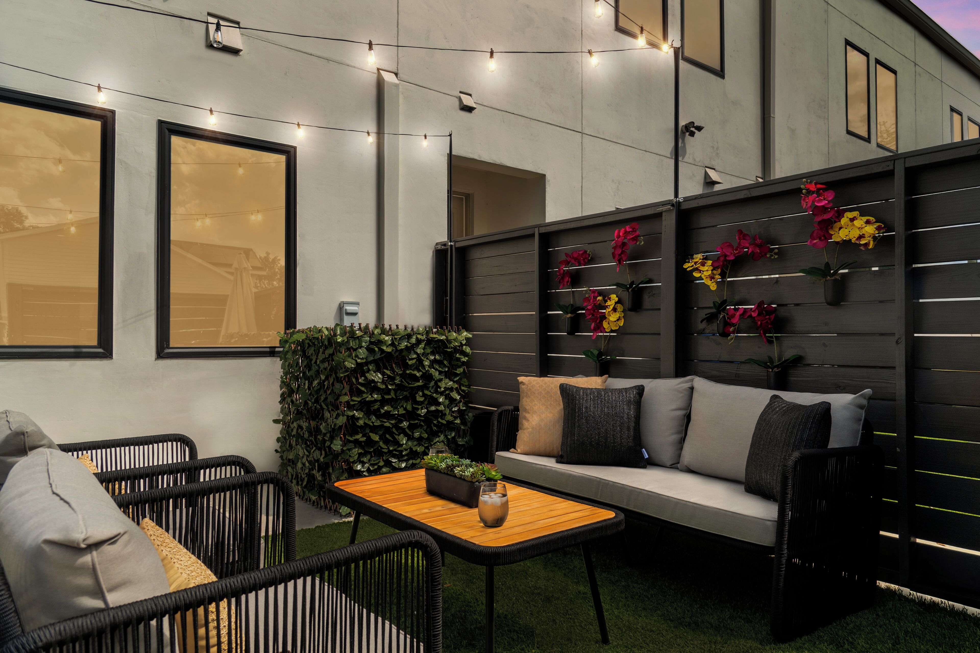 Un espace extérieur aménagé avec un canapé, des chaises, une table et des guirlandes lumineuses.