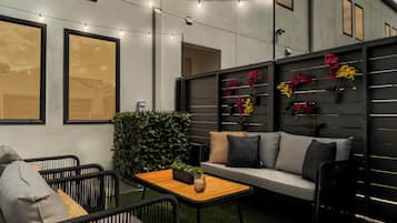 Un espace extérieur aménagé avec un canapé, des chaises, une table et des guirlandes lumineuses.
