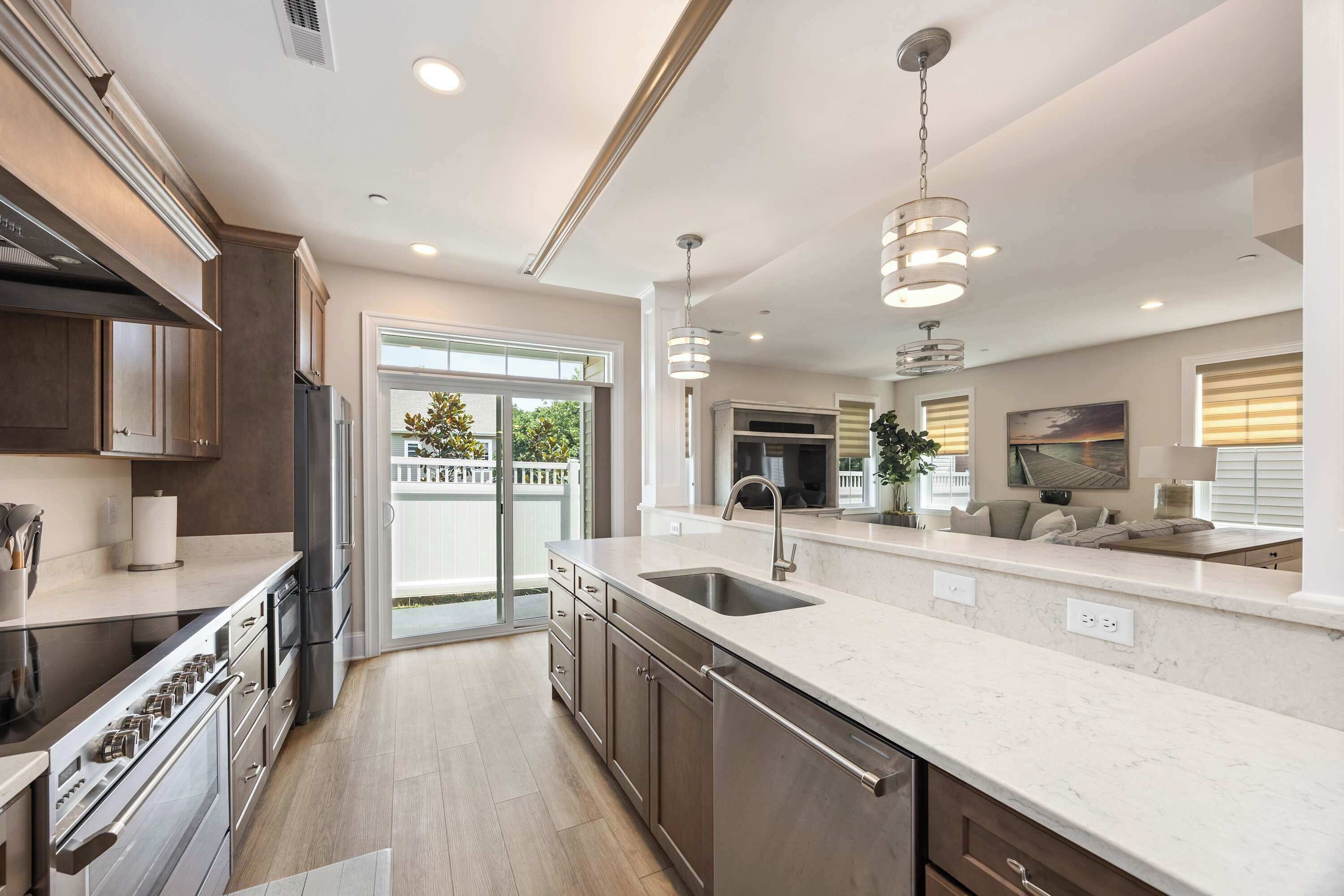 A modern kitchen with a large island, stainless steel appliances, and a sliding glass door leading to a patio.