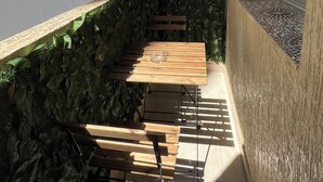 A balcony with a wooden table and chairs, a stone wall, and a view of buildings. - Cozy 2-bedroom apartment in Tanger city center (Tanger)