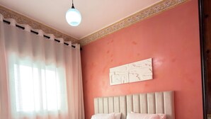A double bed with a headboard, a bedside table with a lamp, and a decorative wall piece. - Cozy 2-bedroom apartment in Tanger city center (Tanger)