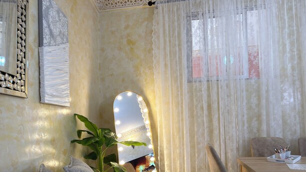 A living room with a sofa, a table with chairs, a mirror with lights, and a plant. - Cozy 2-bedroom apartment in Tanger city center (Tanger)