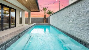 Une piscine avec un mur en pierre, un plafond en bois et des guirlandes lumineuses.