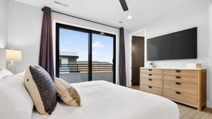 Une chambre d’hôtel moderne dotée d’un grand lit, d’un téléviseur à écran plat, d’une commode en bois et d’un balcon avec vue.