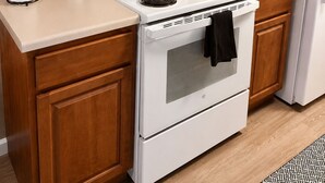 Una cocina con armarios de madera, una estufa blanca, una cafetera y un letrero que dice 'Eat'.