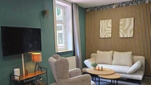 Ett modernt vardagsrum med en soffa, fåtölj, soffbord, en platt-TV och en lampa.