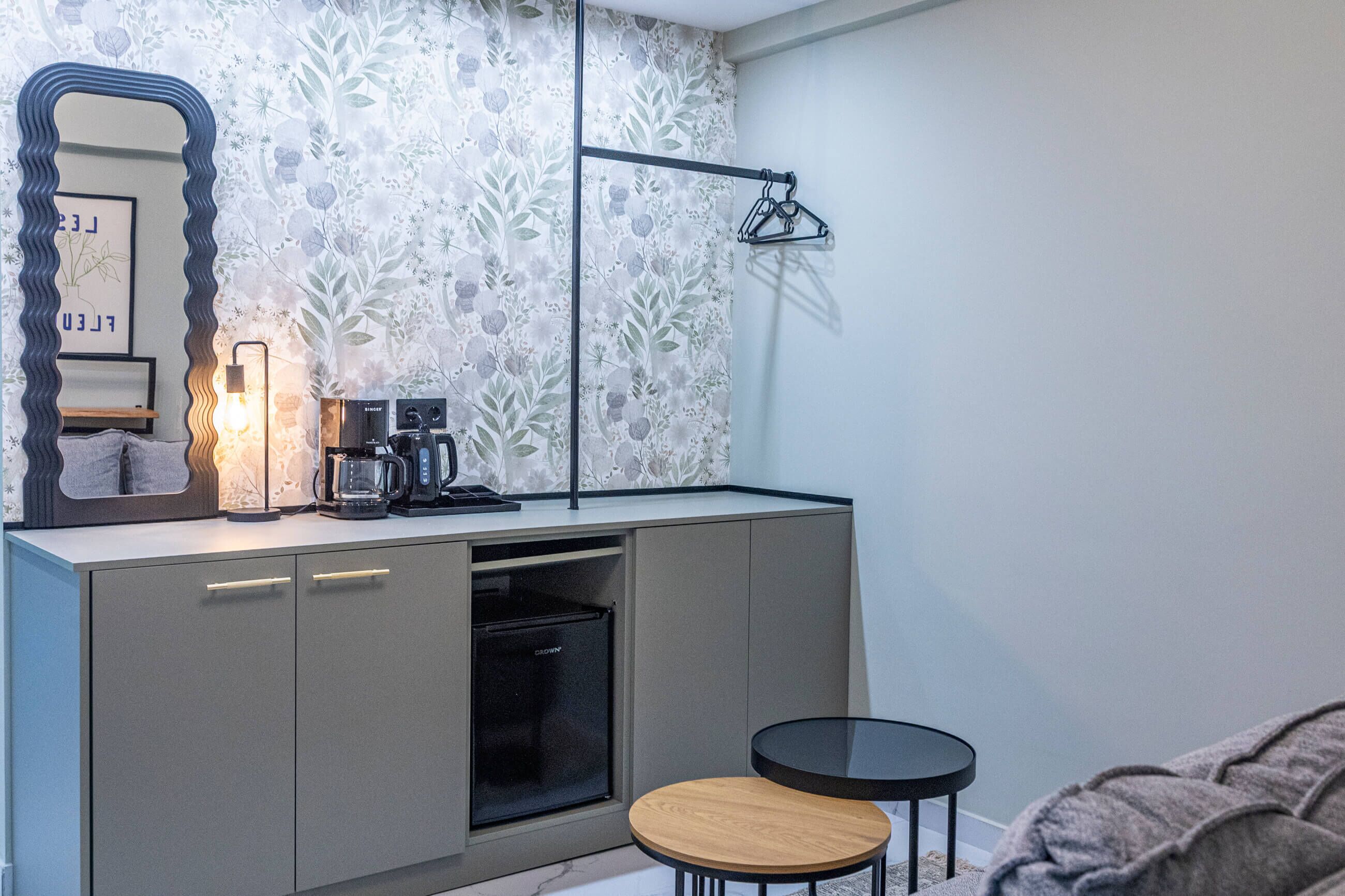A compact kitchenette with a coffee maker, a small refrigerator, and a mirror.