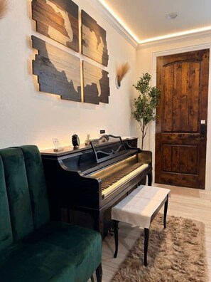 Un piano, un sofá verde, una puerta de madera y decoración en la pared.
