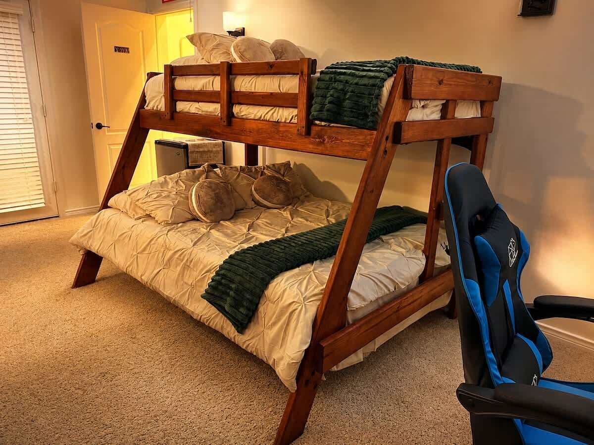 Una cama litera con escritorio y silla, suelo alfombrado y una puerta con un letrero.