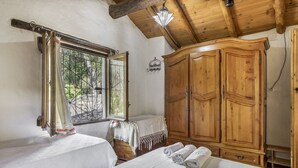 A bedroom with two beds, wooden wardrobe, and a window with a view.