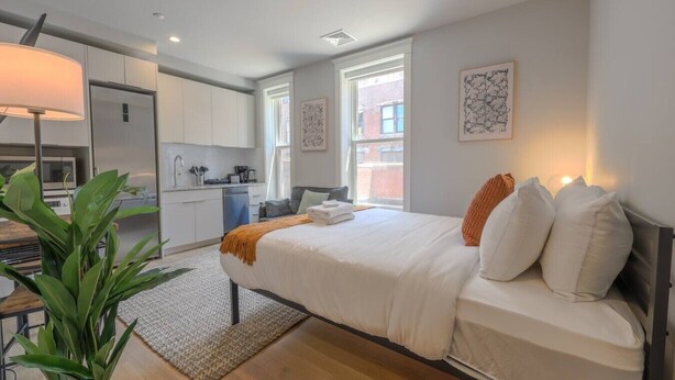 Un dormitorio moderno con una cama grande, lámparas de noche y vistas a la ciudad.