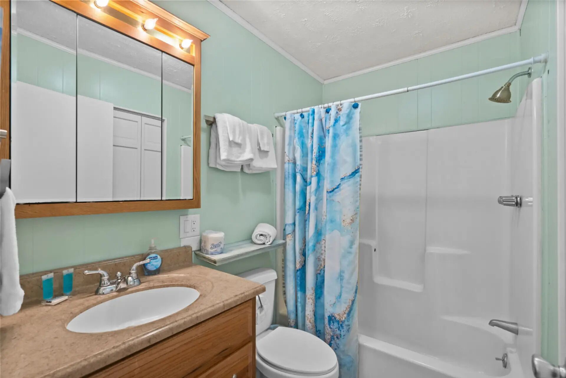 A bathroom with a sink, mirror, toilet, and shower.