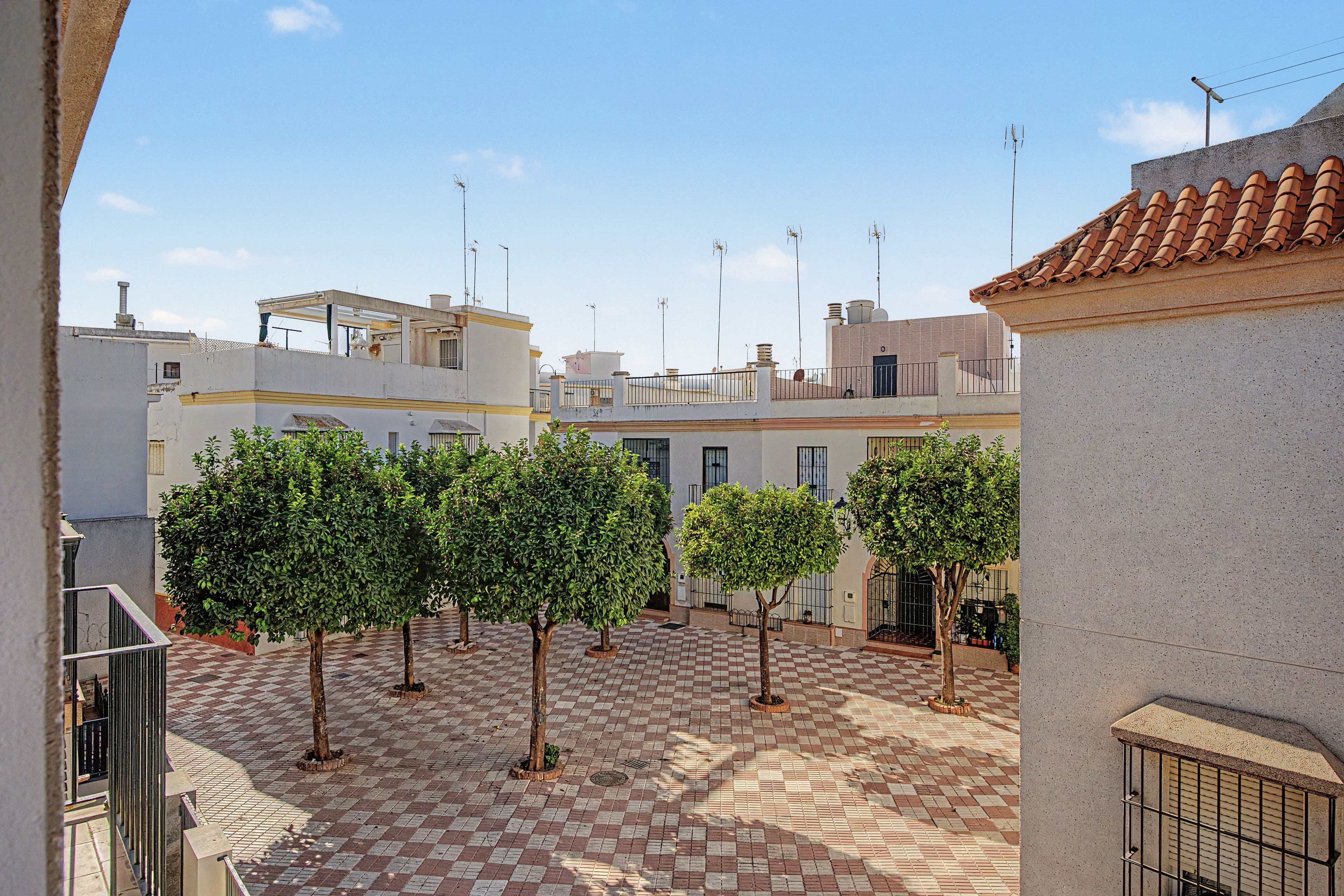 Une cour avec un sol à carreaux, entourée de bâtiments à toits plats et dotés de nombreuses antennes.