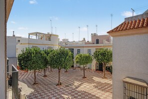 Un patio con piso a cuadros, rodeado de edificios con techos planos y múltiples antenas.
