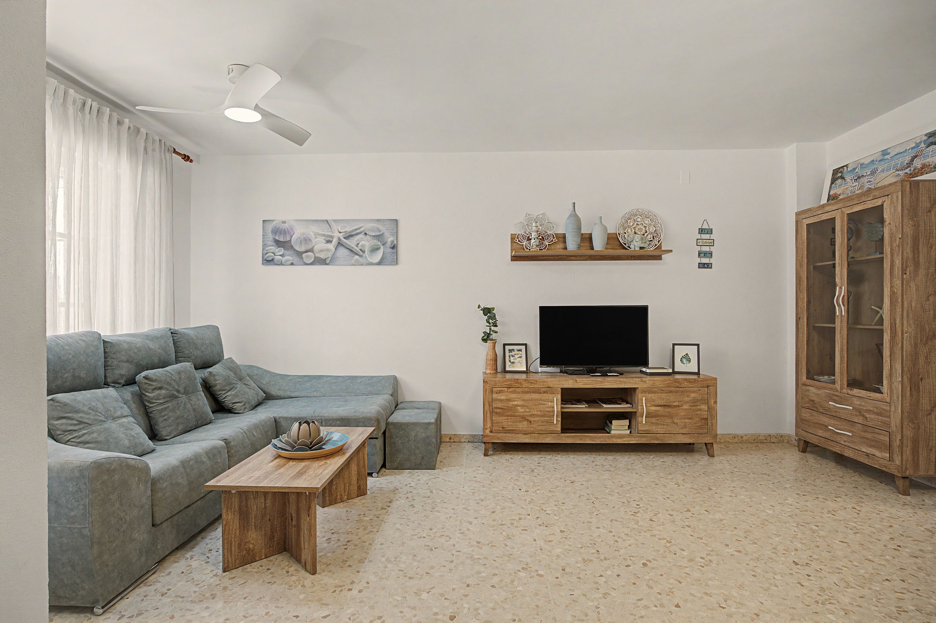 A living room with a grey sofa, a coffee table, a TV stand, and a wooden cabinet.