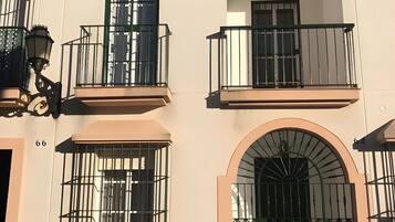 Um edifício com várias varandas, uma grande entrada em arco e uma escadaria que leva à entrada.