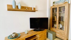 Ein Wohnzimmer mit einer Holztrennwand, einem Flachbildfernseher, einer Vitrine und einem Regal mit Dekoration.
