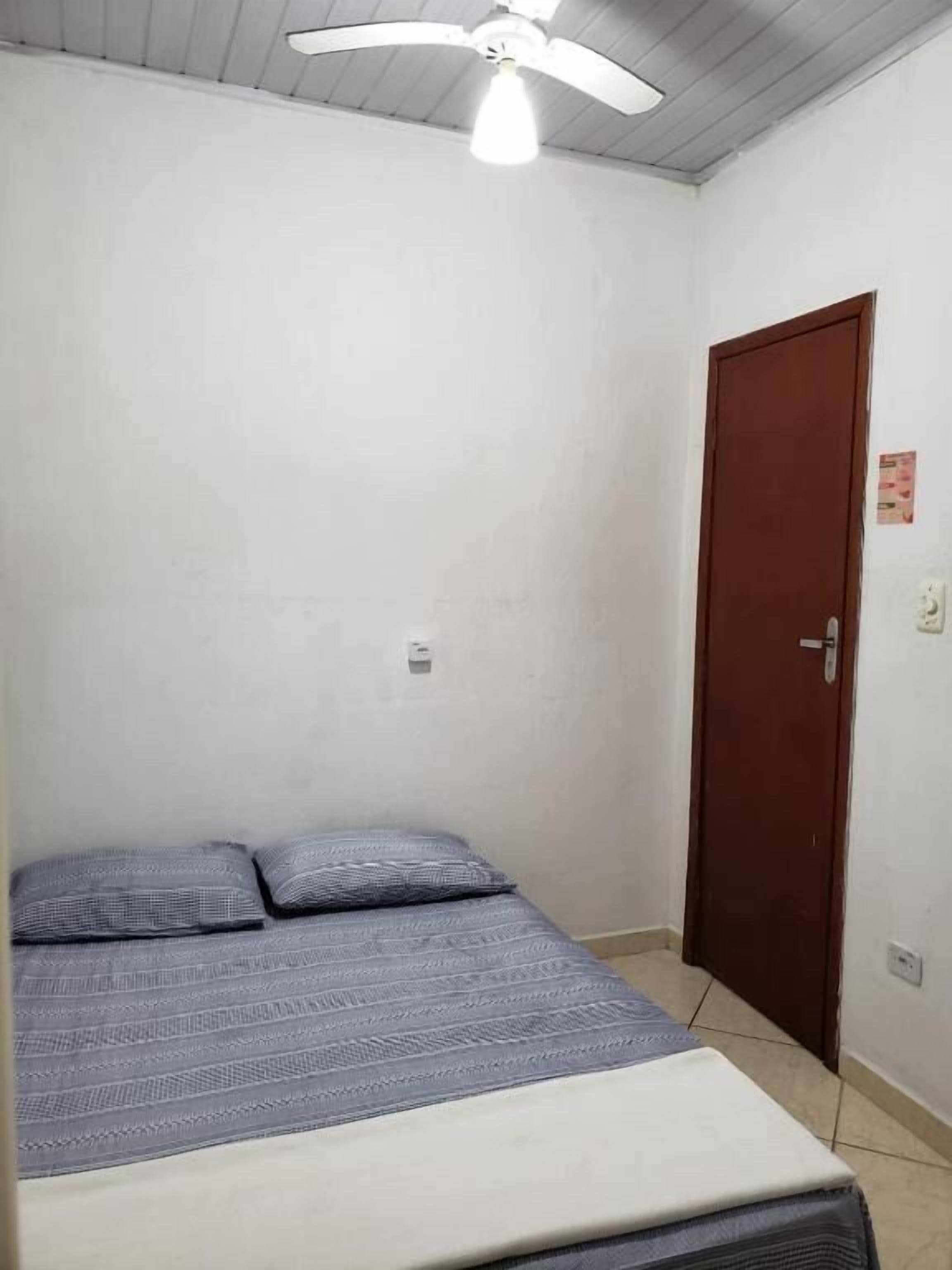 Une chambre à coucher avec un lit, un ventilateur de plafond, une porte et un interrupteur.