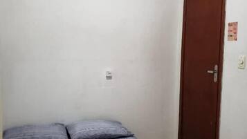 Une chambre à coucher avec un lit, un ventilateur de plafond, une porte et un interrupteur.
