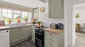 A kitchen with a dishwasher, stove, and toaster. There is a window with a view of greenery outside. - Pet-Friendly Cottage w/ Garden Near Malton (Malton)