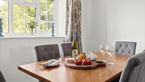 A dining table with a bottle, glasses, bread, tomatoes, and a cheese board. - Pet-Friendly Cottage w/ Garden Near Malton (Malton)