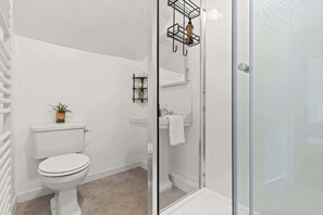 Een badkamer met toilet, wastafel en douche.