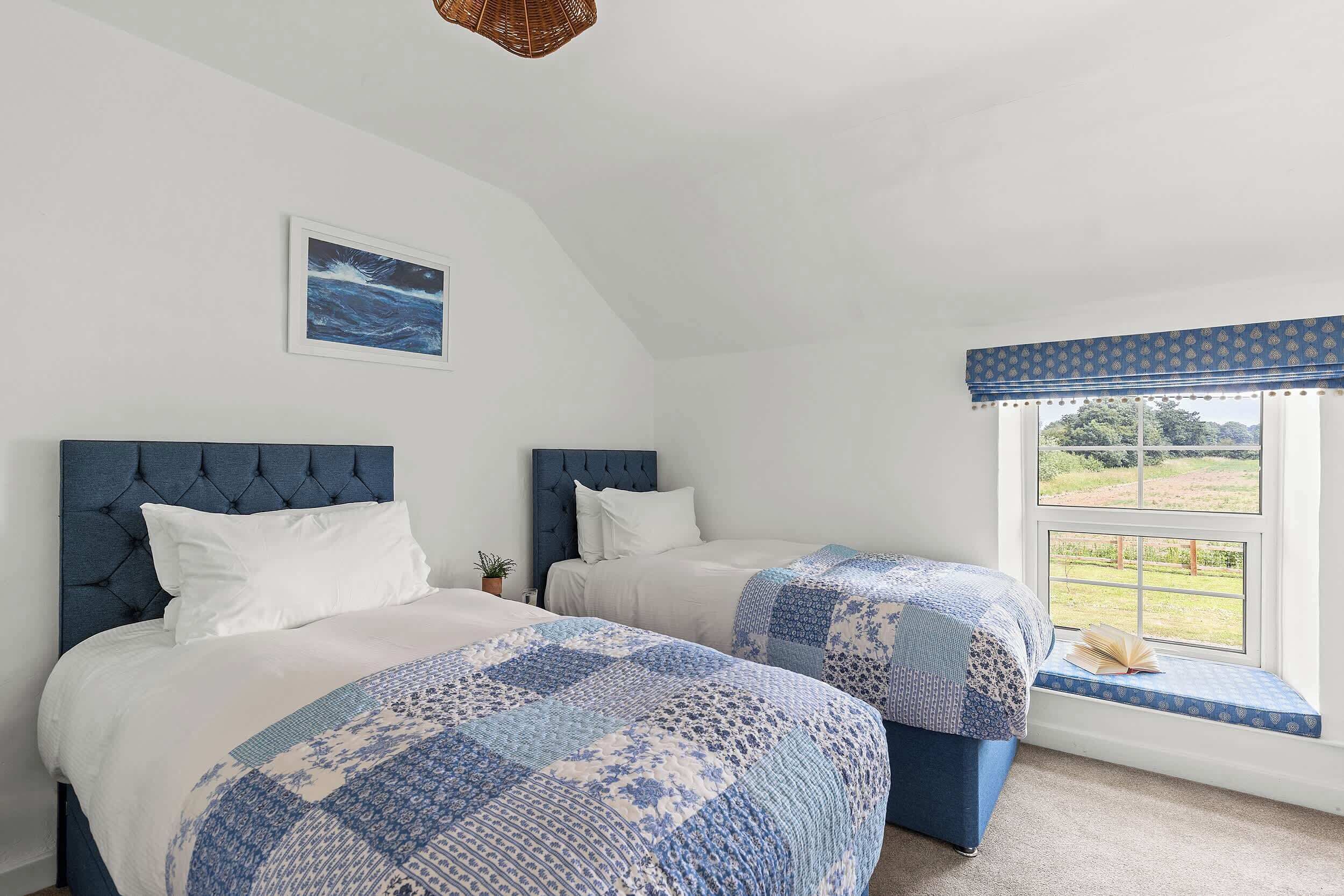 Une chambre avec deux lits, une fenêtre donnant sur un beau paysage et un tableau accroché au mur.