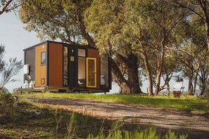 Una cabaña moderna y compacta con fachada de madera, puerta de vidrio y un pequeño porche.