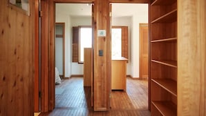 A wooden interior with a wooden floor, a door, and a shelf unit.