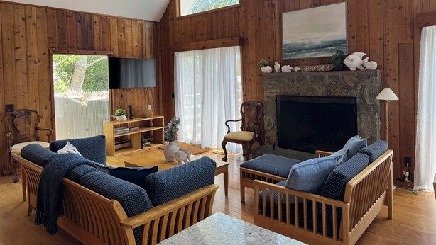 A cozy cabin interior with wooden walls, a fireplace, a television, and comfortable seating.