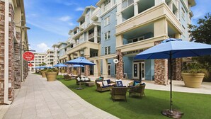 Une cour d’hôtel avec des places assises en plein air, une façade en briques et une enseigne indiquant un marché.