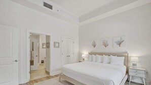 Une chambre à coucher avec un grand lit, des tables de chevet, une porte et un couloir.