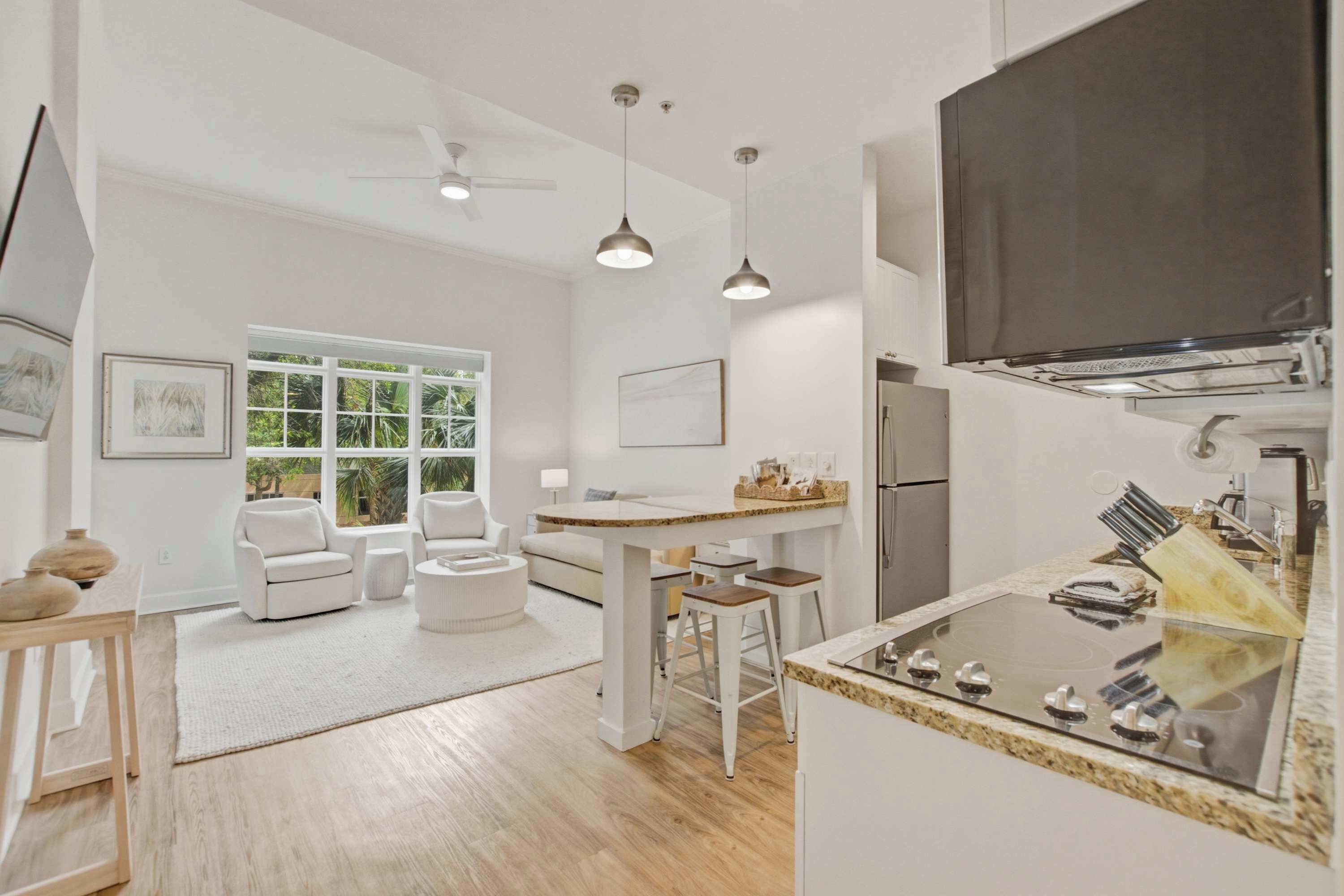 A modern kitchen with a central island, bar stools, and a large refrigerator.